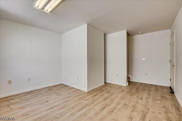 spare room featuring baseboards and light wood-style flooring