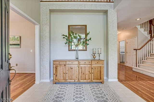 foyer entrance featuring baseboards, stairs, and light tile patterned floors