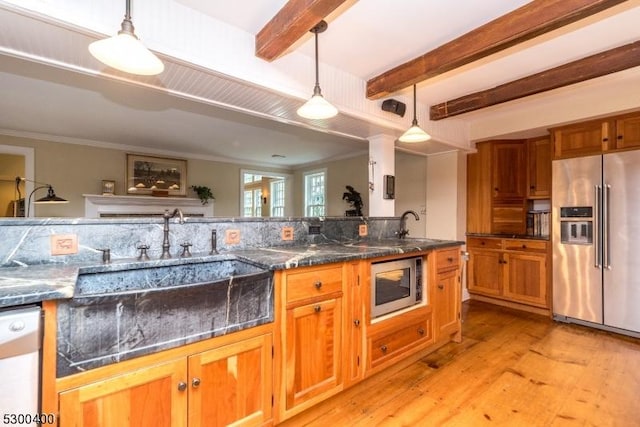 kitchen with stainless steel appliances, decorative light fixtures, light wood-style floors, brown cabinets, and a sink