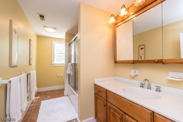 bathroom with combined bath / shower with glass door, visible vents, vanity, and baseboards