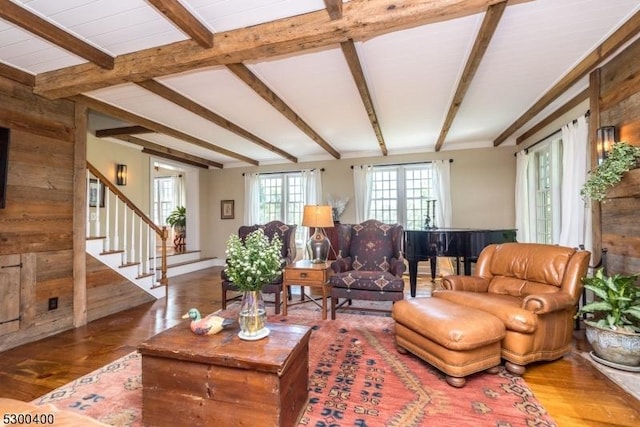 living room featuring stairway, wood finished floors, and vaulted ceiling with beams