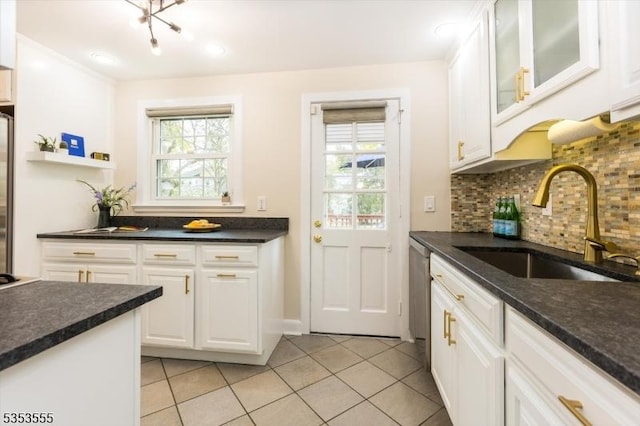 kitchen featuring light tile patterned floors, a sink, tasteful backsplash, and a healthy amount of sunlight