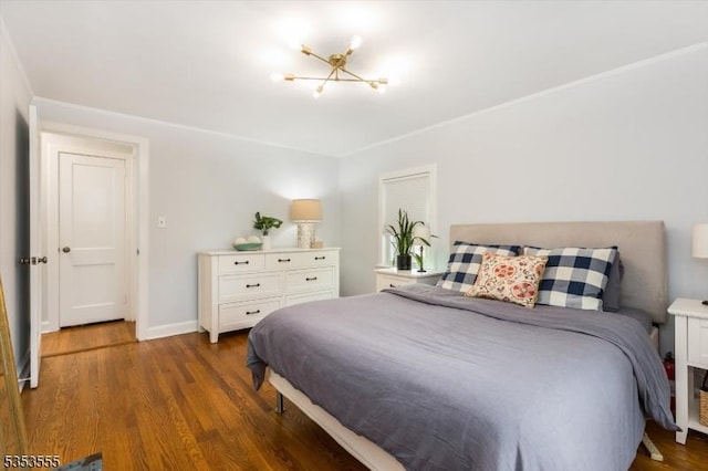 bedroom featuring an inviting chandelier, wood finished floors, and baseboards