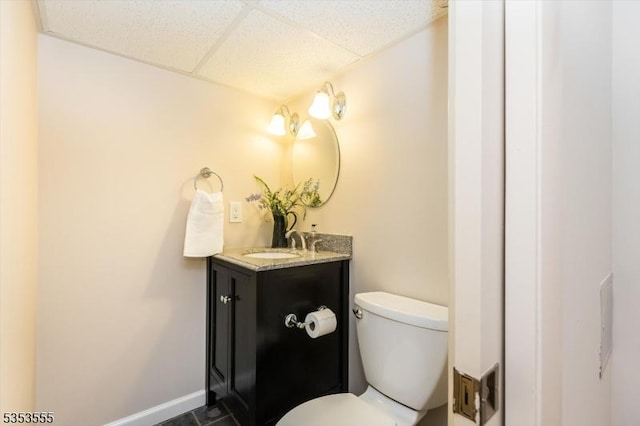 bathroom featuring toilet, a drop ceiling, and vanity