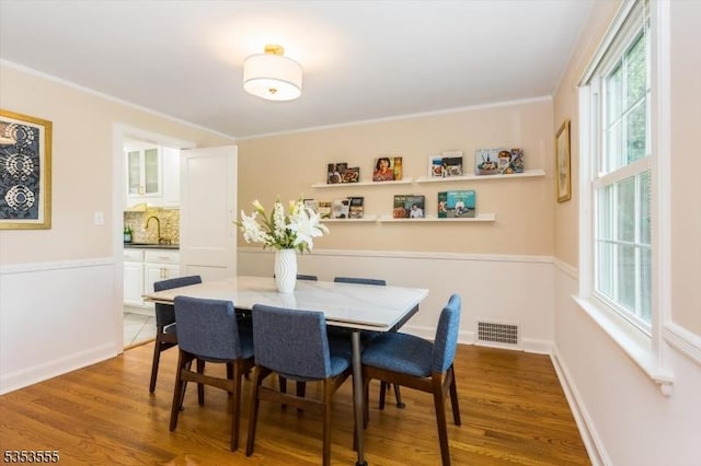 dining room with ornamental molding, wood finished floors, and visible vents