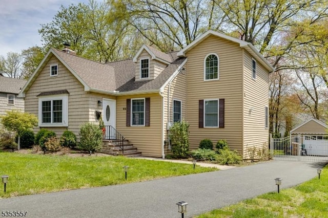 view of front of home with an outbuilding, a shingled roof, a chimney, and a front yard