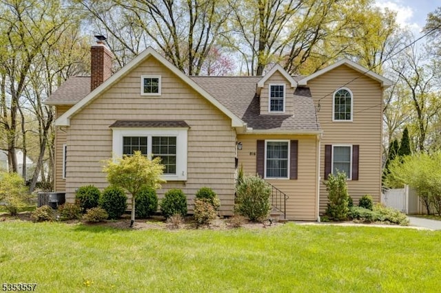 view of front of house with a chimney, a shingled roof, and a front lawn
