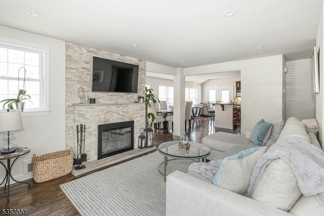 living area with baseboards, dark wood-style flooring, and a fireplace