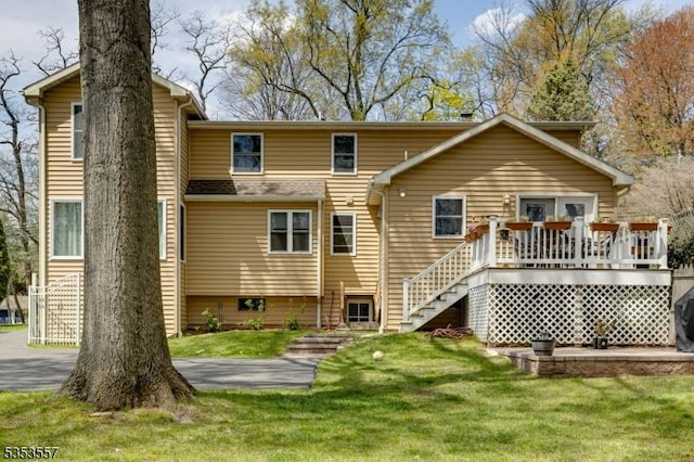 back of property with a yard, a wooden deck, and stairs