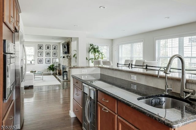 kitchen featuring beverage cooler, a healthy amount of sunlight, a sink, and dark stone countertops