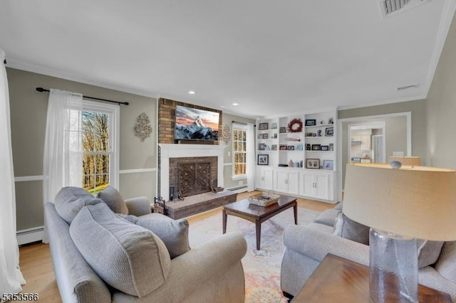 living area with recessed lighting, a baseboard radiator, built in shelves, a fireplace, and visible vents