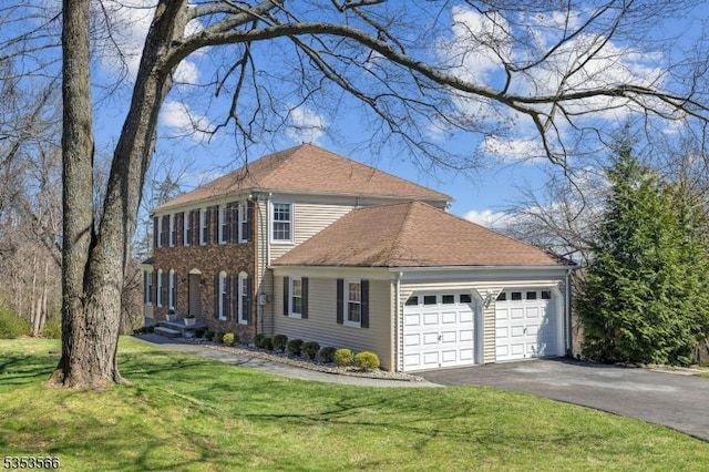 colonial-style house with a front lawn, an attached garage, and aphalt driveway