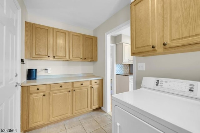 clothes washing area with light tile patterned flooring, cabinet space, and washer / dryer