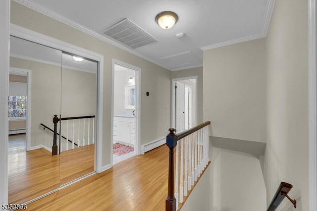 corridor featuring an upstairs landing, wood finished floors, visible vents, and a baseboard radiator