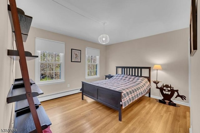 bedroom featuring baseboards, wood finished floors, and a baseboard heating unit