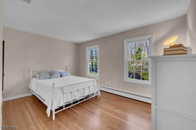 bedroom with baseboards, wood finished floors, and a baseboard radiator