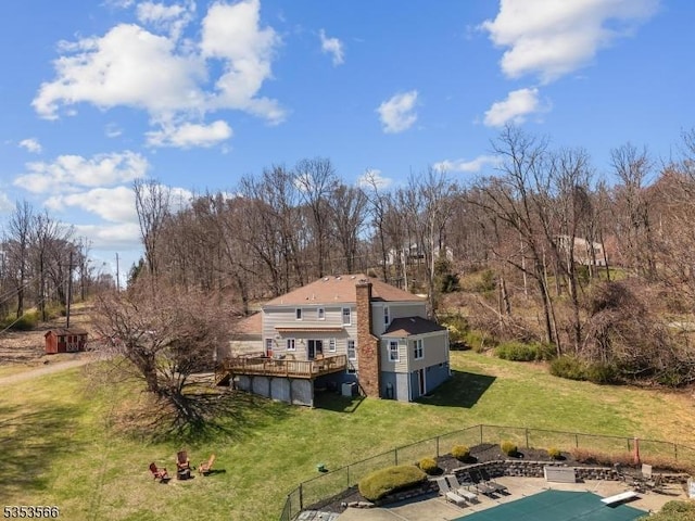 back of house featuring fence, a deck, a yard, and a chimney