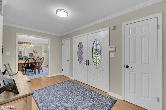 entryway with baseboards, light wood-type flooring, a notable chandelier, and crown molding