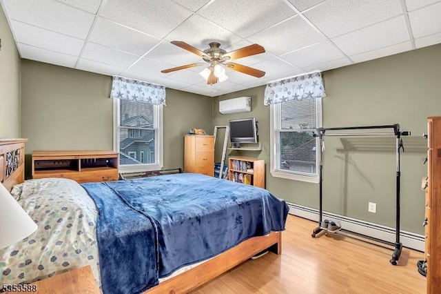 67 May St, Hawthorne Boro, NJ 07506 - bedroom with a drop ceiling, baseboard heating, an AC wall unit, wood finished floors, and a ceiling fan