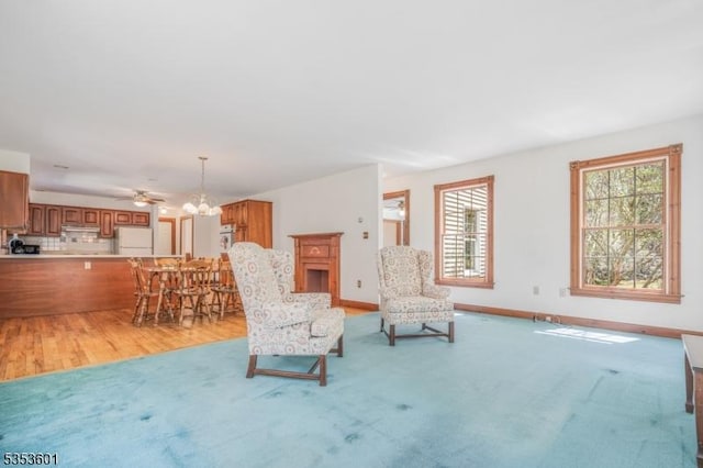 living area with baseboards, a chandelier, light carpet, and light wood-style floors