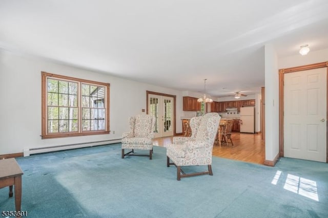 sitting room featuring light colored carpet, baseboards, a baseboard heating unit, and a chandelier