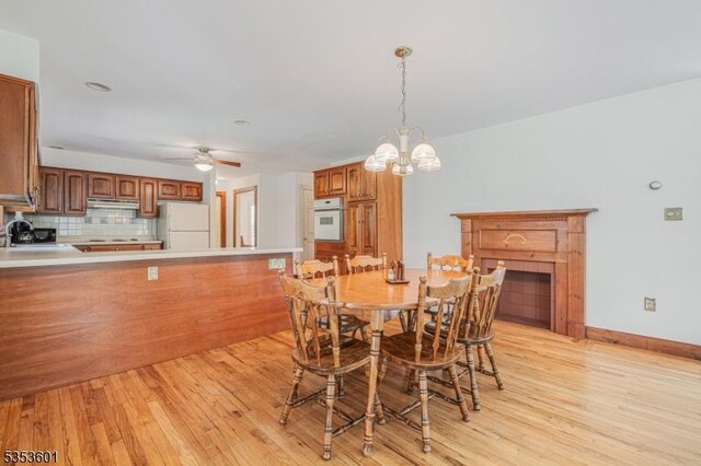 dining room featuring light wood-type flooring, baseboards, and ceiling fan with notable chandelier