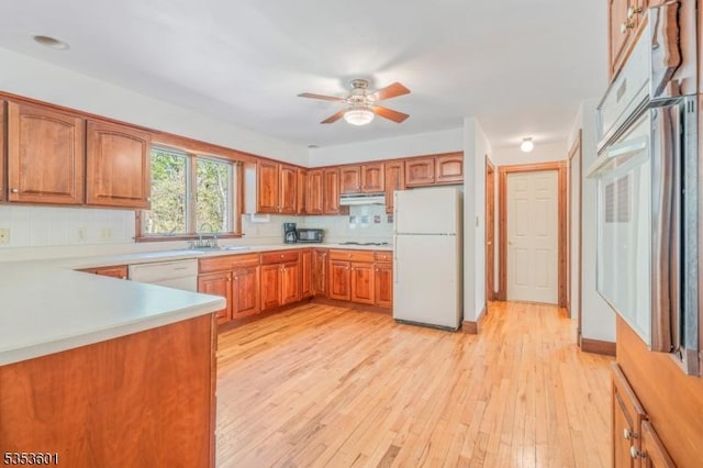 kitchen featuring a sink, tasteful backsplash, a ceiling fan, and white appliances
