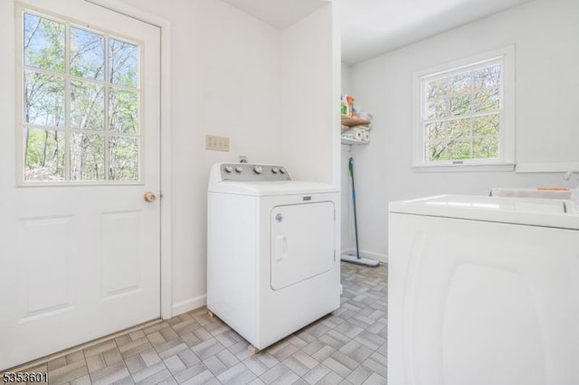 laundry area with washer and dryer, laundry area, brick patterned floor, and baseboards