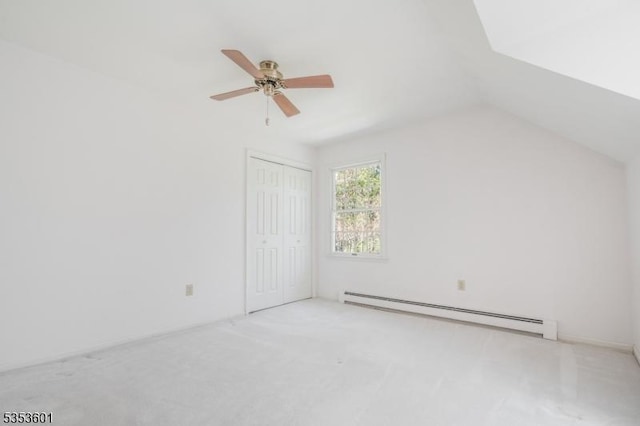 interior space with a ceiling fan, vaulted ceiling, a baseboard heating unit, and carpet