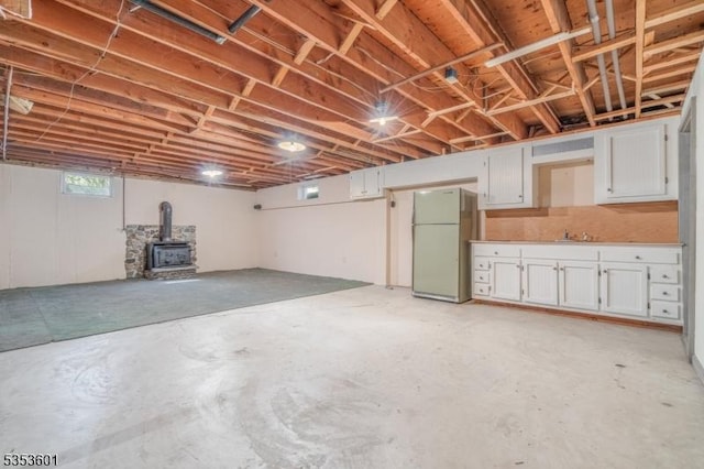 below grade area with freestanding refrigerator and a wood stove