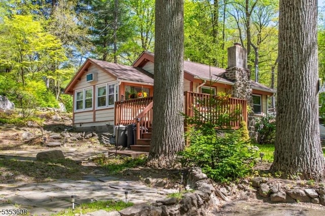 rear view of house featuring a sunroom, a wooden deck, and a chimney