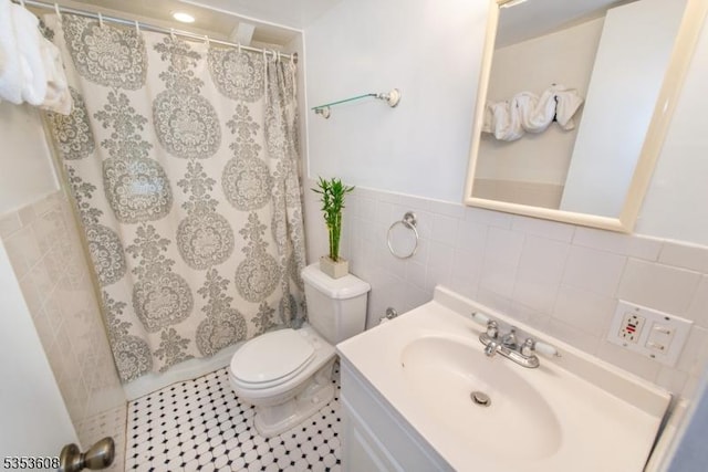 bathroom with vanity, wainscoting, curtained shower, toilet, and tile walls