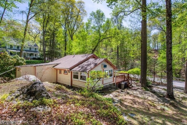 view of property exterior featuring roof with shingles and a wooden deck