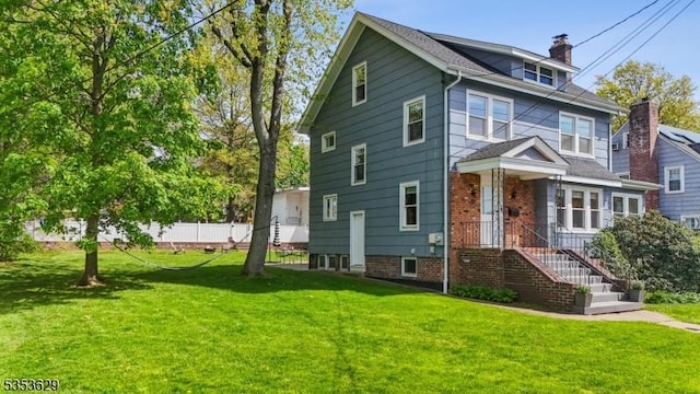 american foursquare style home featuring fence, a front yard, and a chimney