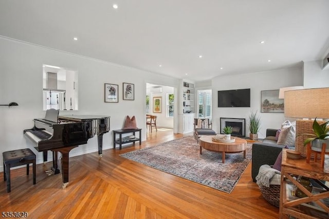 living room featuring recessed lighting, crown molding, a fireplace, and light wood-type flooring