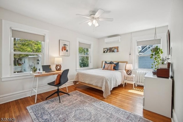 bedroom featuring radiator heating unit, multiple windows, and a wall mounted air conditioner