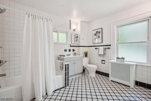 bathroom with radiator heating unit, tile walls, shower / bath combo, and toilet