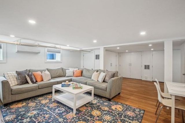 living area with an AC wall unit, recessed lighting, wood finished floors, and visible vents