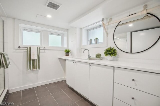 bathroom featuring tile patterned flooring, vanity, baseboards, an enclosed shower, and visible vents