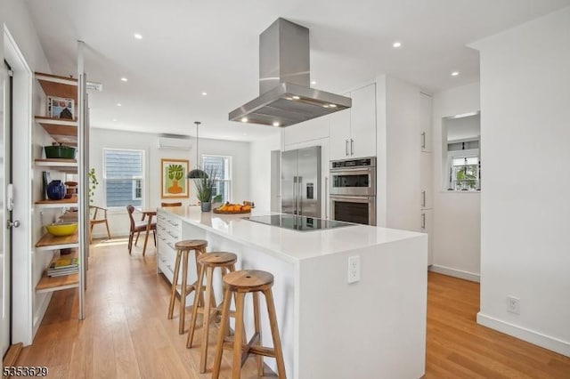 kitchen with stainless steel appliances, white cabinetry, island exhaust hood, a healthy amount of sunlight, and a wall mounted AC