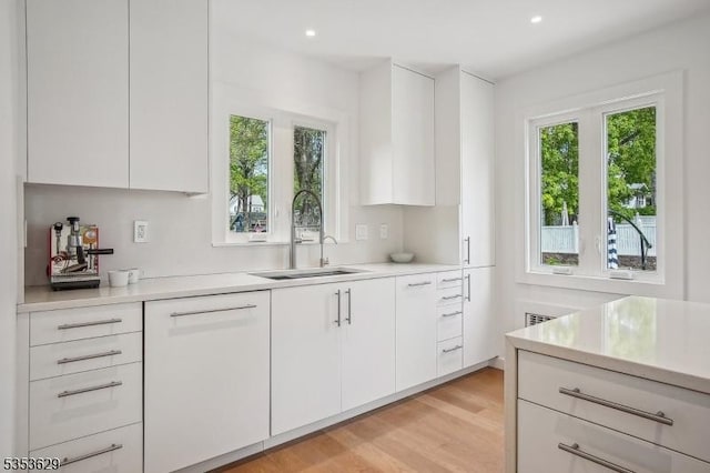 kitchen featuring light countertops, white cabinetry, a sink, and modern cabinets
