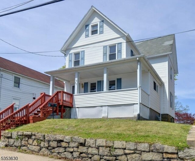 view of front of house featuring covered porch, stairs, and a front yard