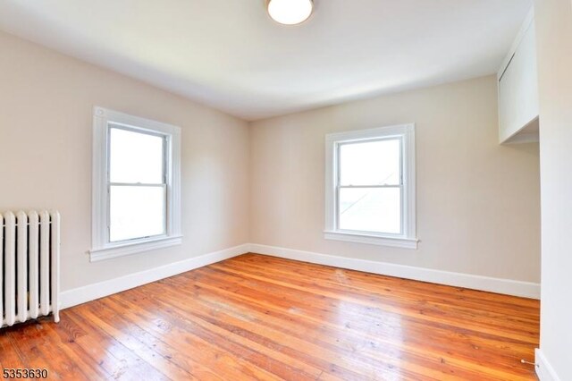 empty room with baseboards, radiator, and a wealth of natural light