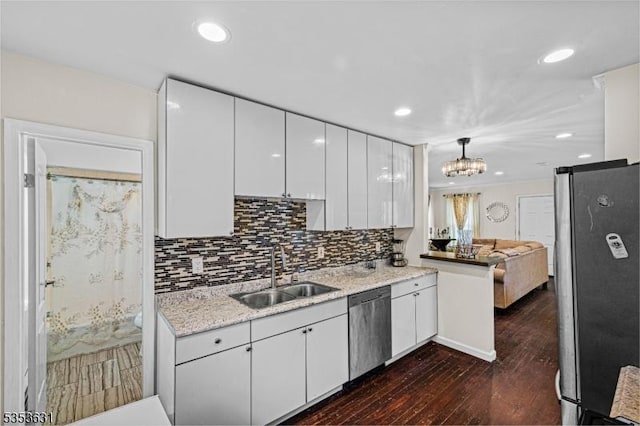 kitchen featuring tasteful backsplash, appliances with stainless steel finishes, a sink, white cabinetry, and dark wood-type flooring