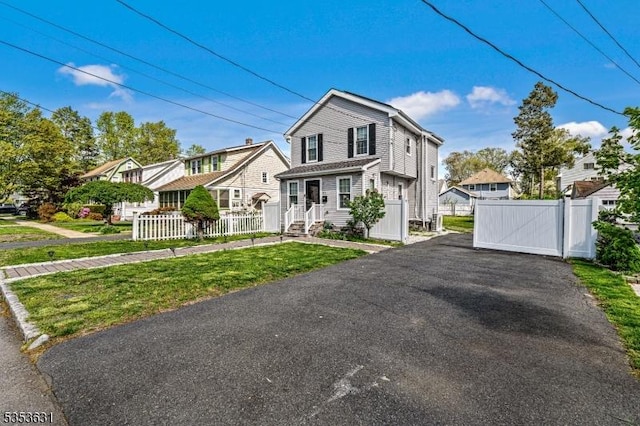 view of front of house featuring a gate, fence, driveway, and a front yard