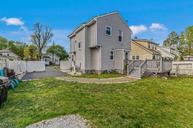 back of property with a lawn, a deck, a patio area, and a fenced backyard