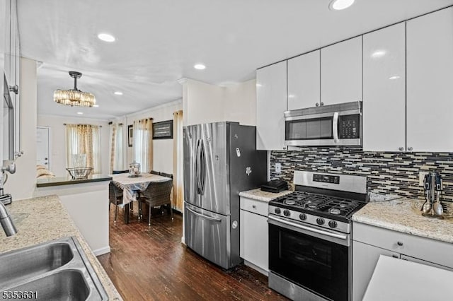 kitchen featuring a sink, dark wood-style flooring, a chandelier, tasteful backsplash, and appliances with stainless steel finishes