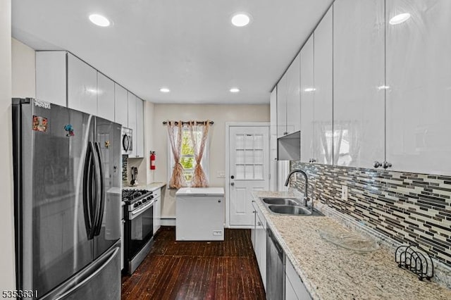 kitchen featuring decorative backsplash, white cabinets, a sink, stainless steel appliances, and dark wood-type flooring