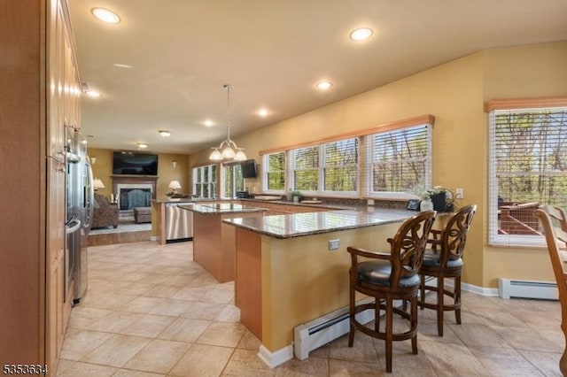 kitchen featuring stainless steel dishwasher, a peninsula, a fireplace, a baseboard heating unit, and dark stone countertops