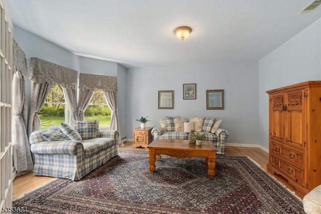 living room with visible vents, a baseboard radiator, light wood-style floors, and baseboards